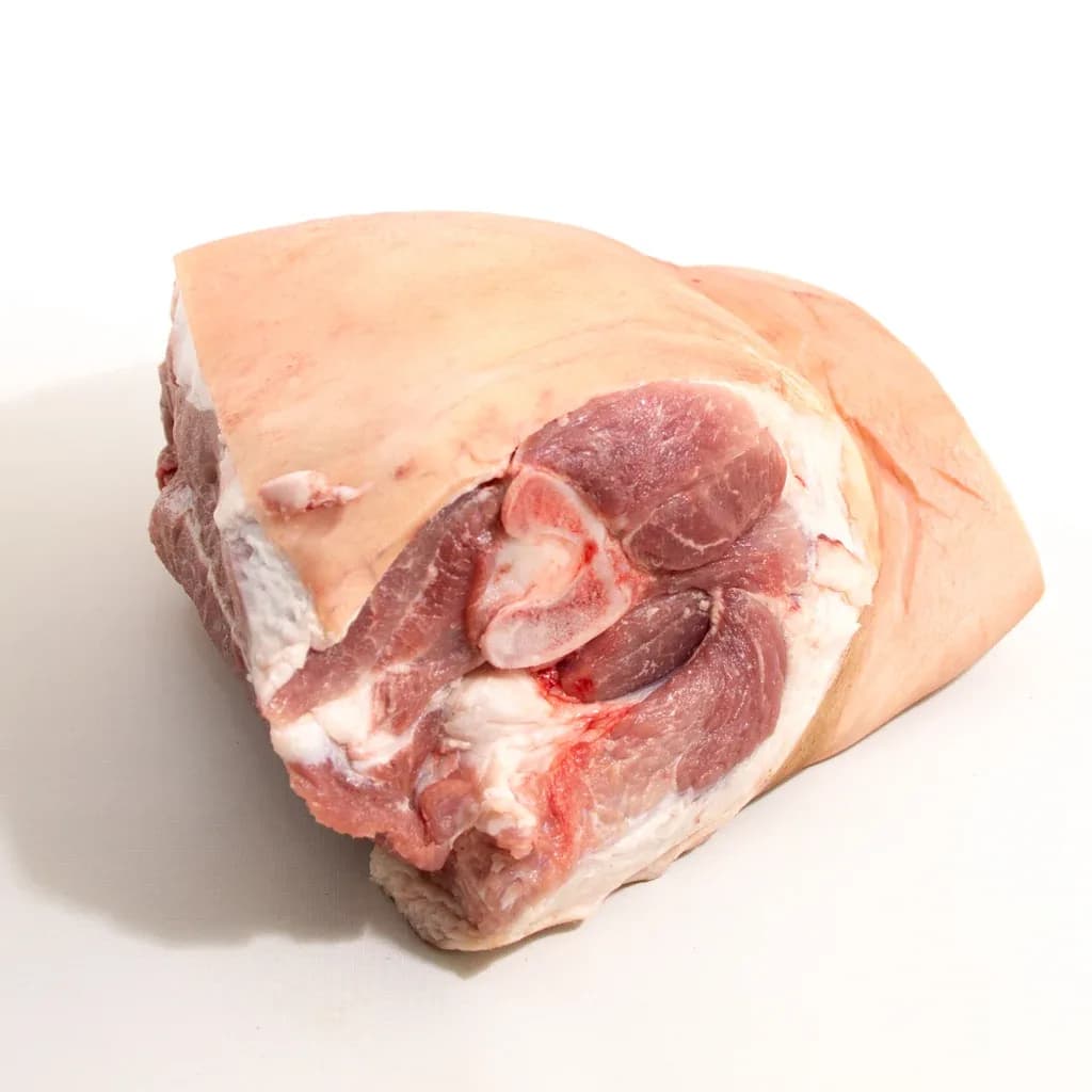 A bone-in, rind-on pork shoulder on a white background, cut face showing the blade bone and surrounding muscle.