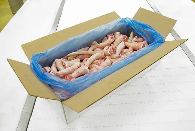 Short pork tails packed in a blue-lined carton on the packing line.